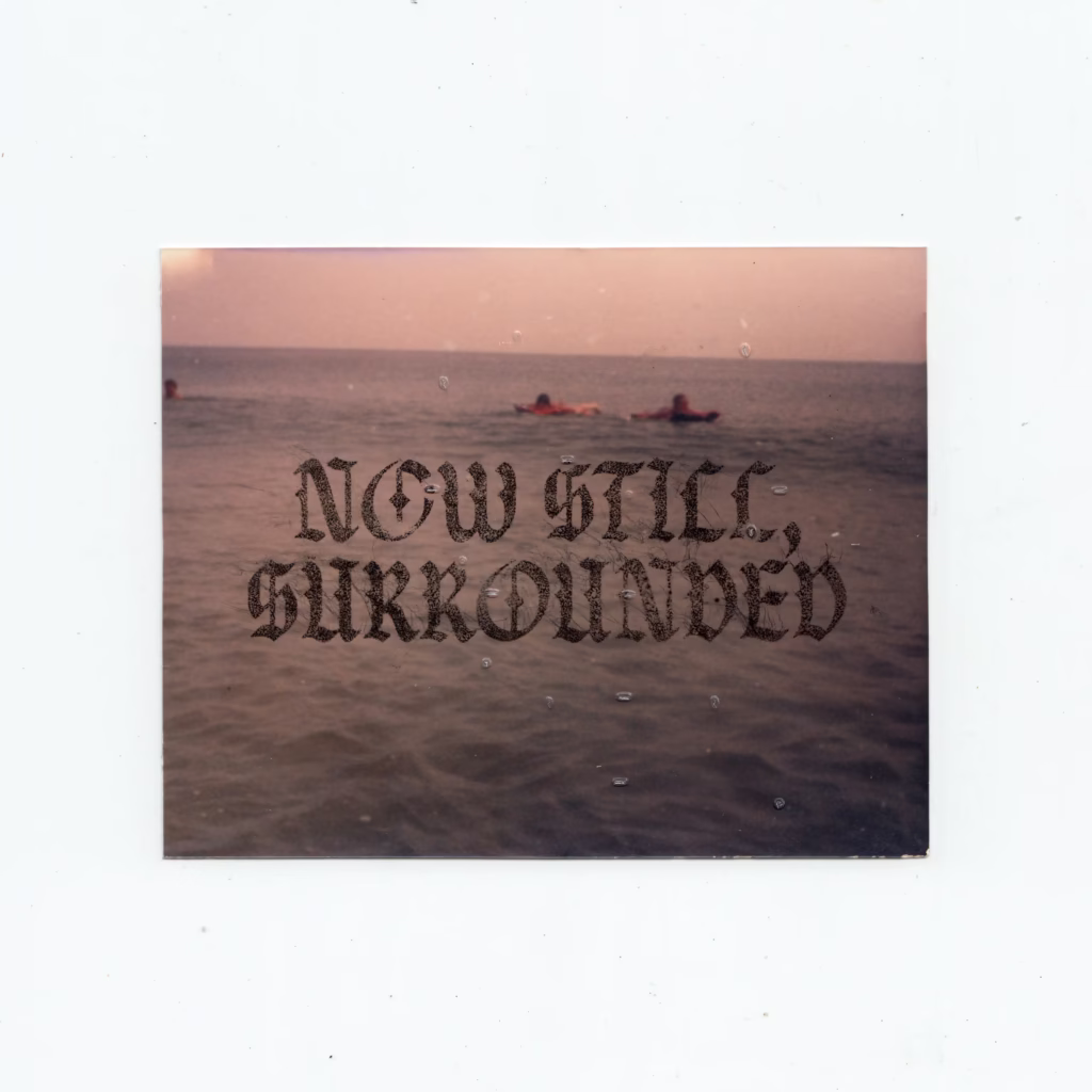 Scan of photograph of people floating in ocean with text NOW STILL, SURROUNDED overlaid